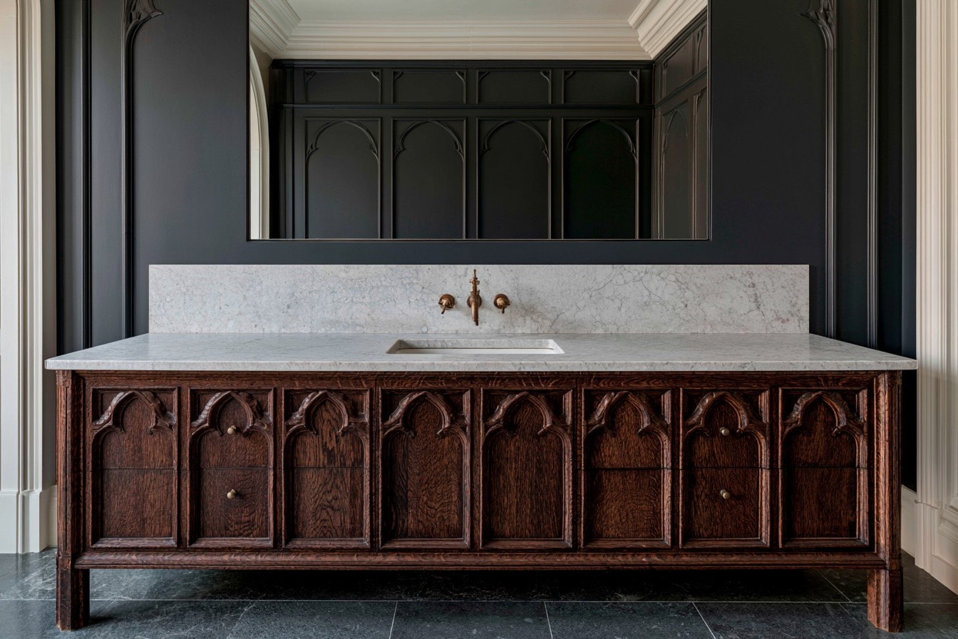 Carved dark wood vanity cabinet in a Gothic bathroom