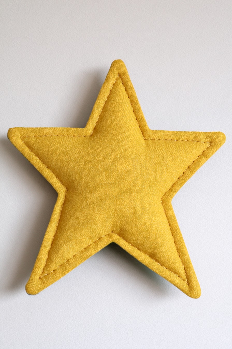 Mustard star shaped pillow with visible edge stitching