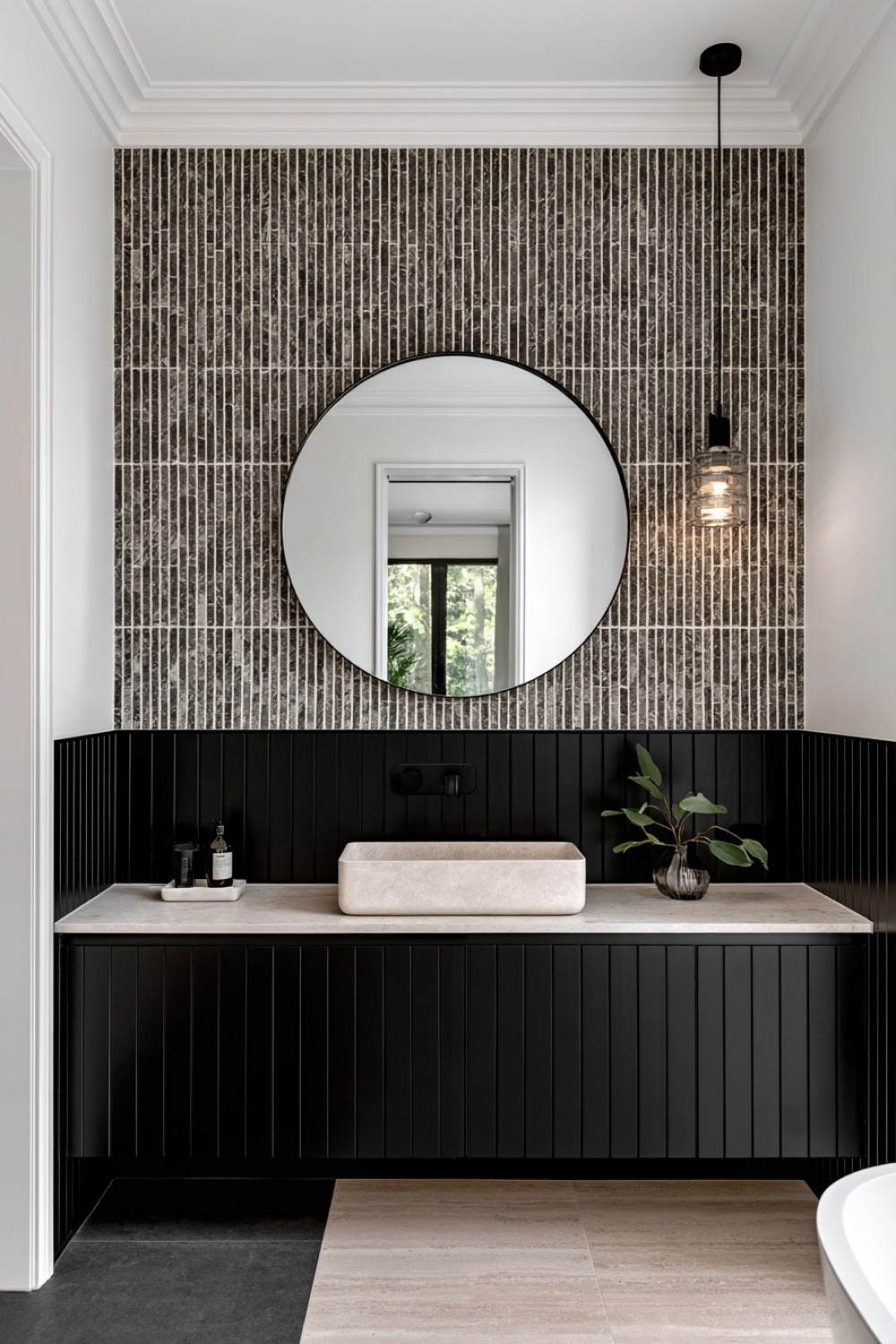 Bathroom wall divided between black lower panels and white upper walls