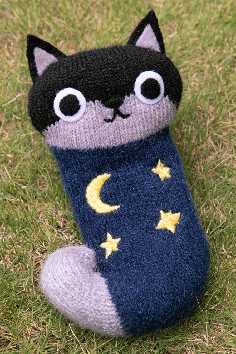 Dark fox sock character with pointed ears, a lavender face and tail, and yellow moon and star motifs