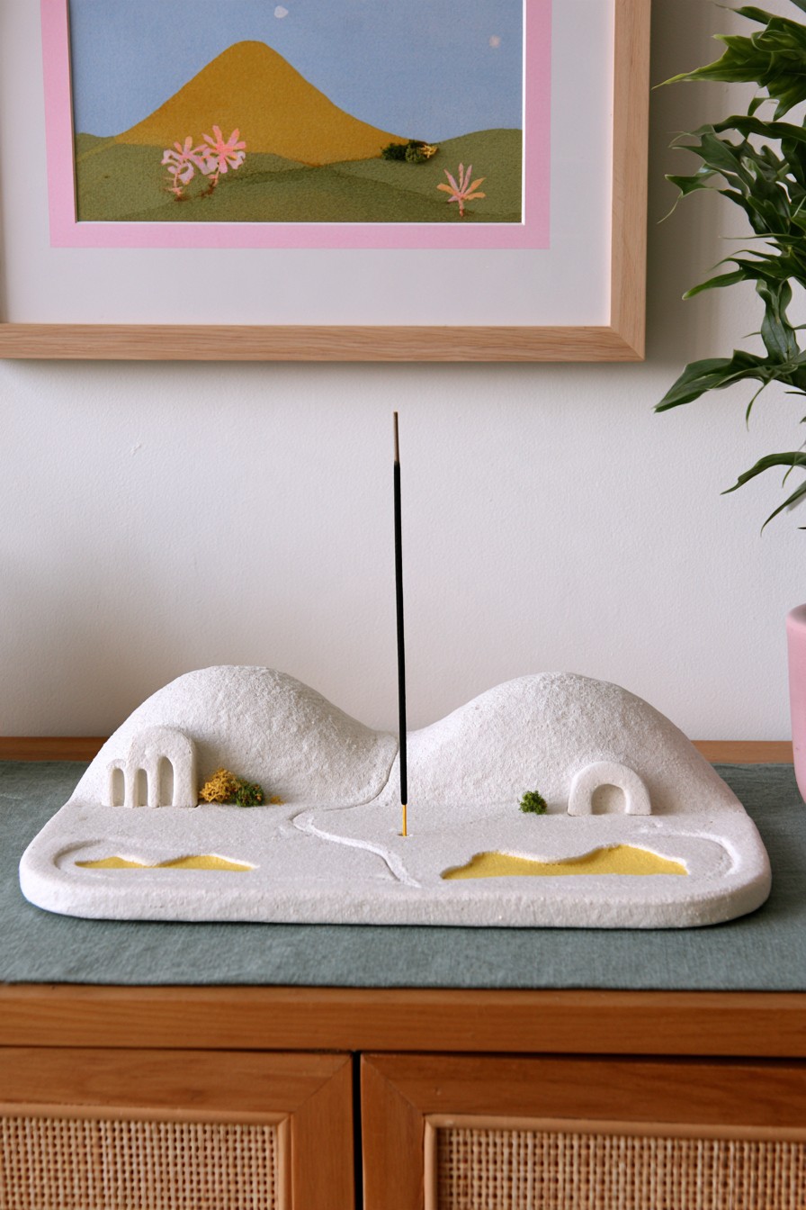 Miniature clay landscape with an unlit decorative stick and architectural openings