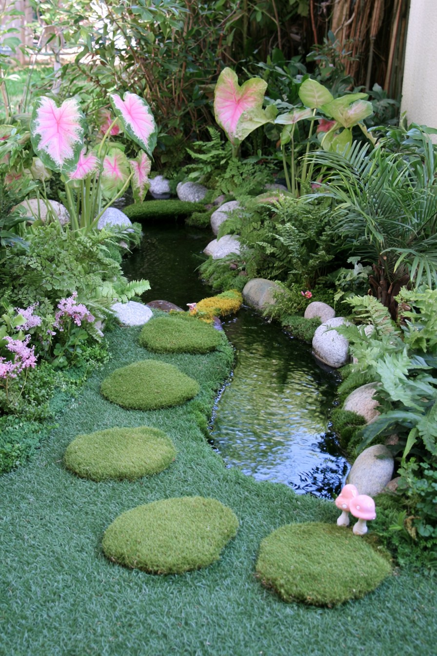Narrow tropical garden stream edged with stones ferns and colorful foliage
