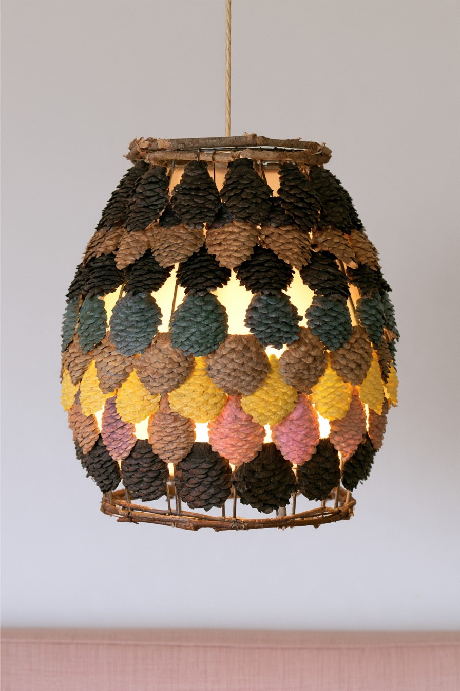 Hanging oval shade form with rows of small pinecones in muted colors