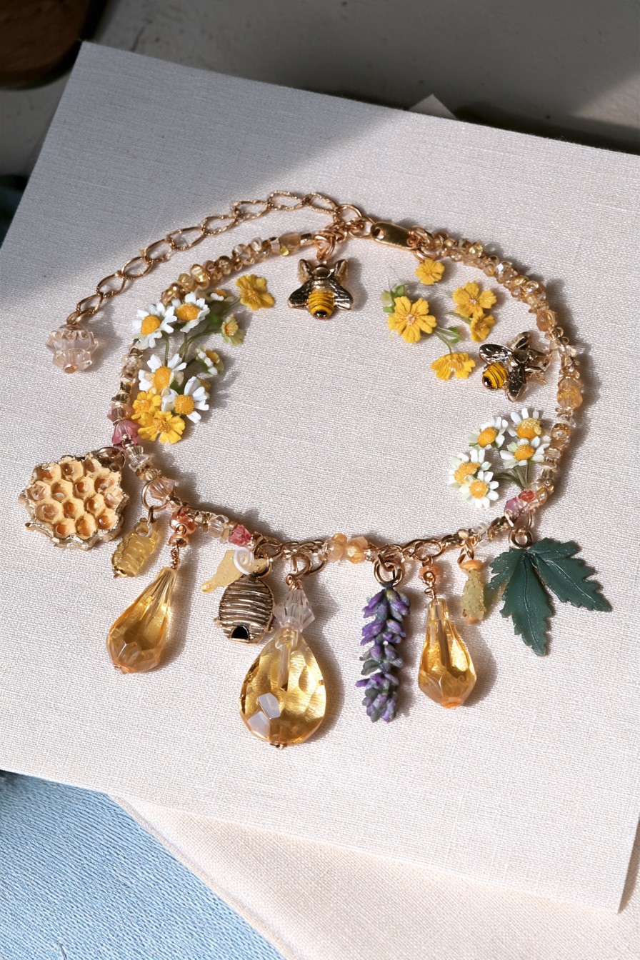 Bee and flower charm bracelet with honeycomb motif and amber colored drops