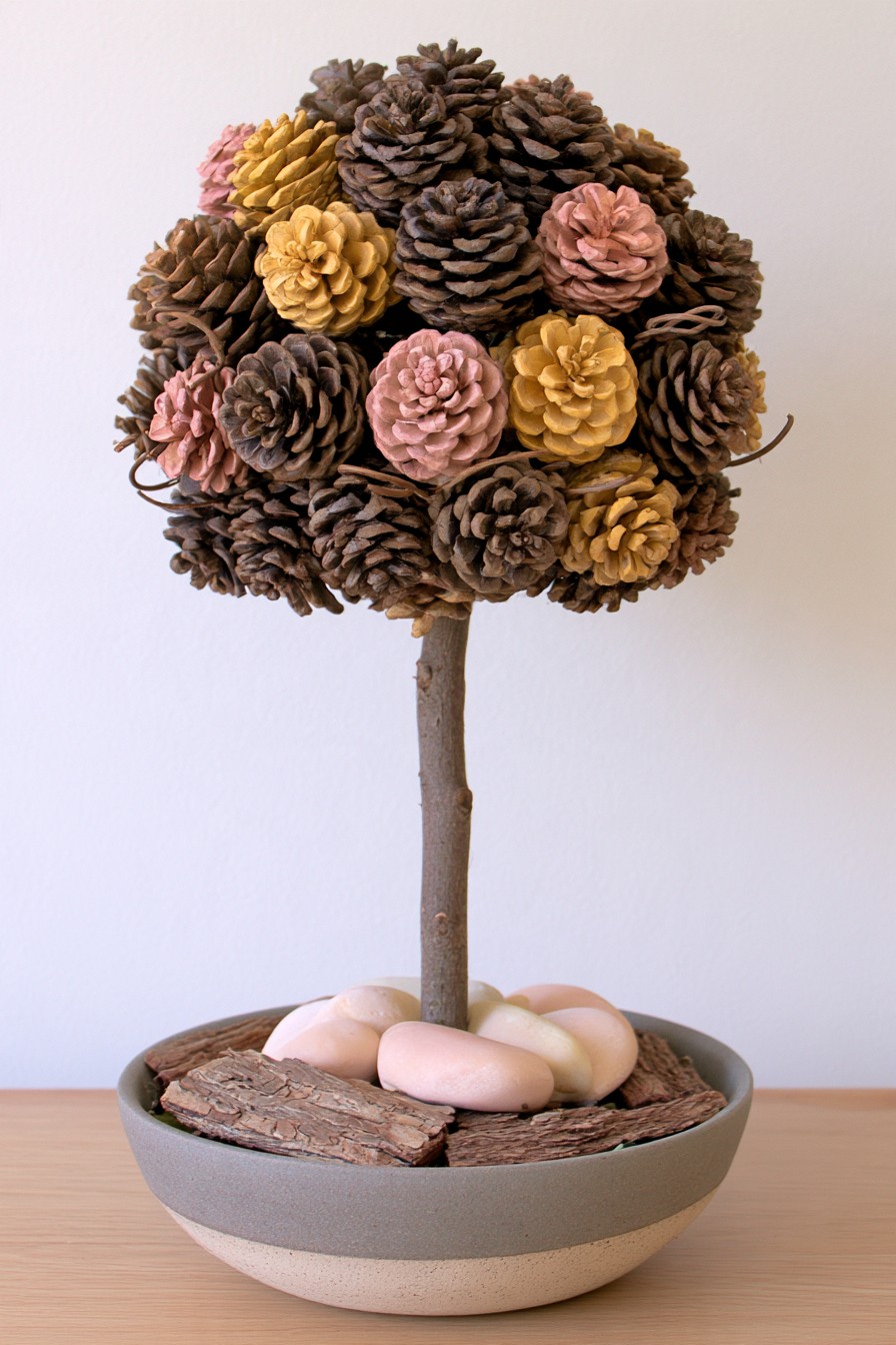 Pinecone topiary with a branch trunk, stone-filled bowl, and bark accents