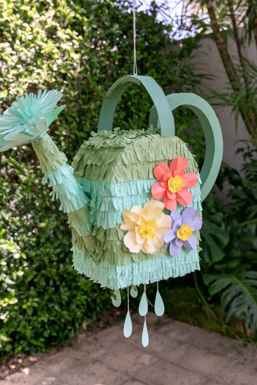 Green watering can piñata decorated with layered paper flowers