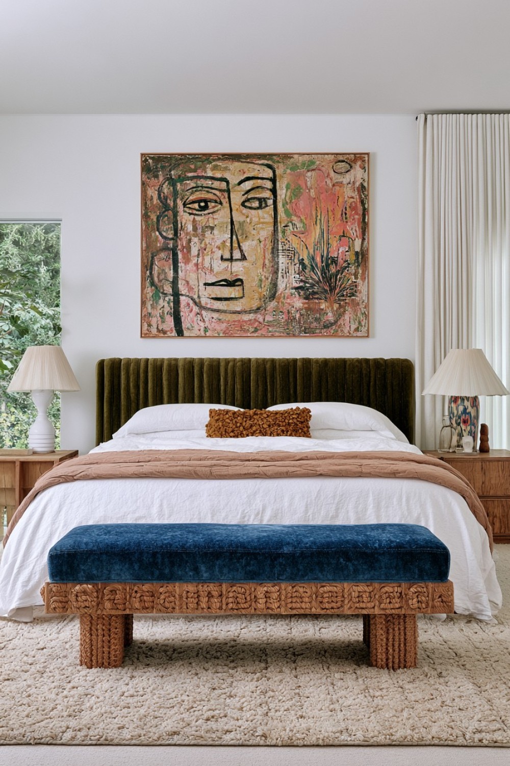 Sculptural bench positioned at the foot of an eclectic bed