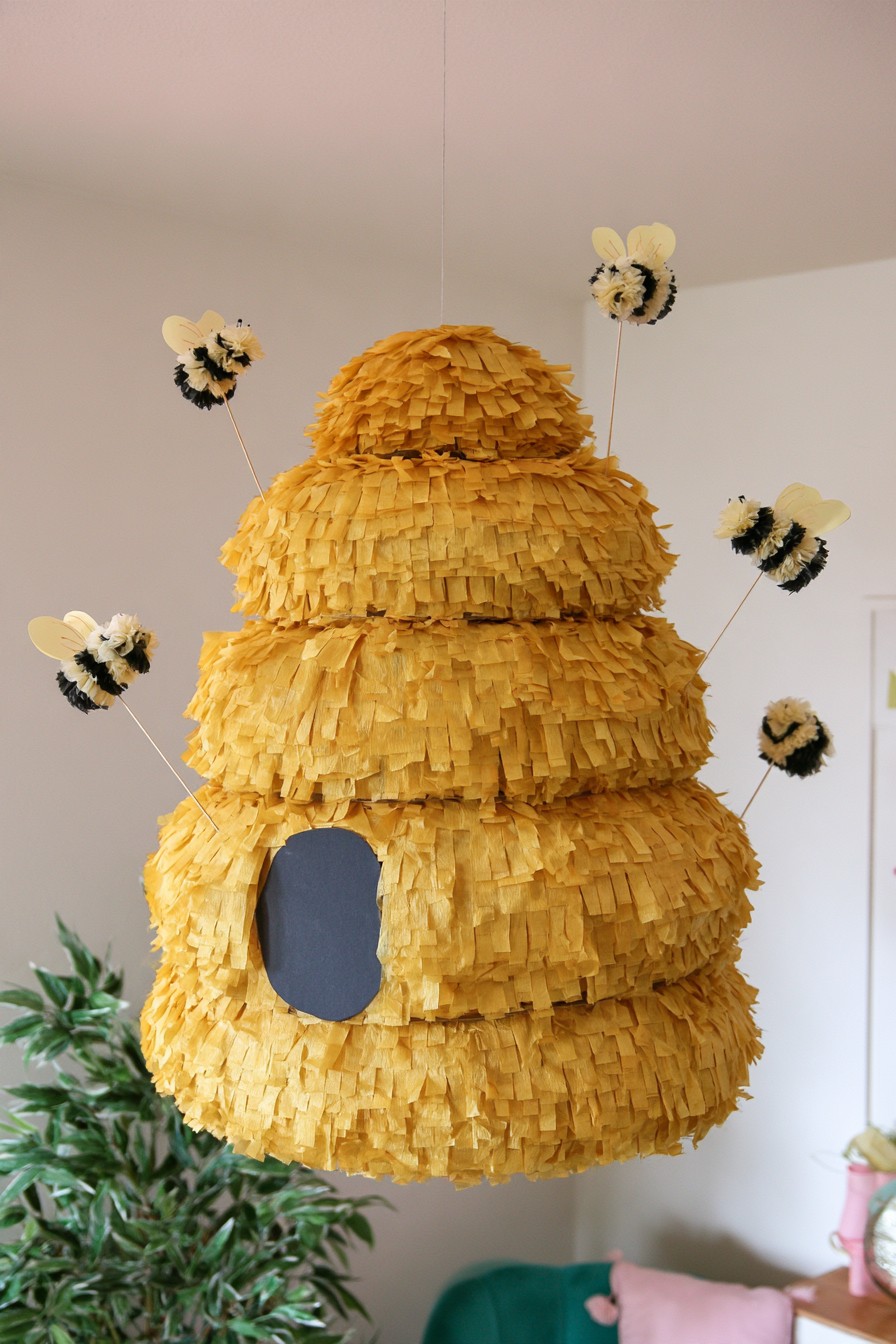 Mustard yellow beehive piñata decorated with small paper bees