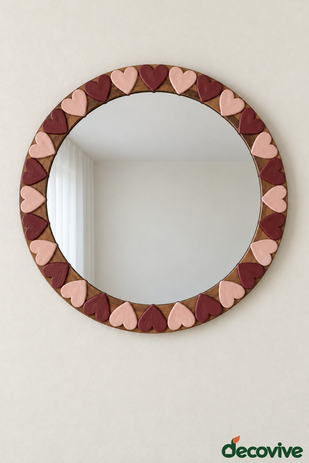 Round wooden mirror frame with flat blush pink and burgundy clay hearts pointing inward