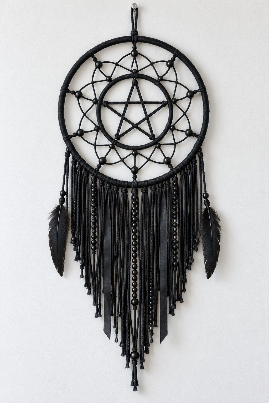 Black double hoop hanging with a central five pointed star, beaded web, long dark fringe and two feather accents