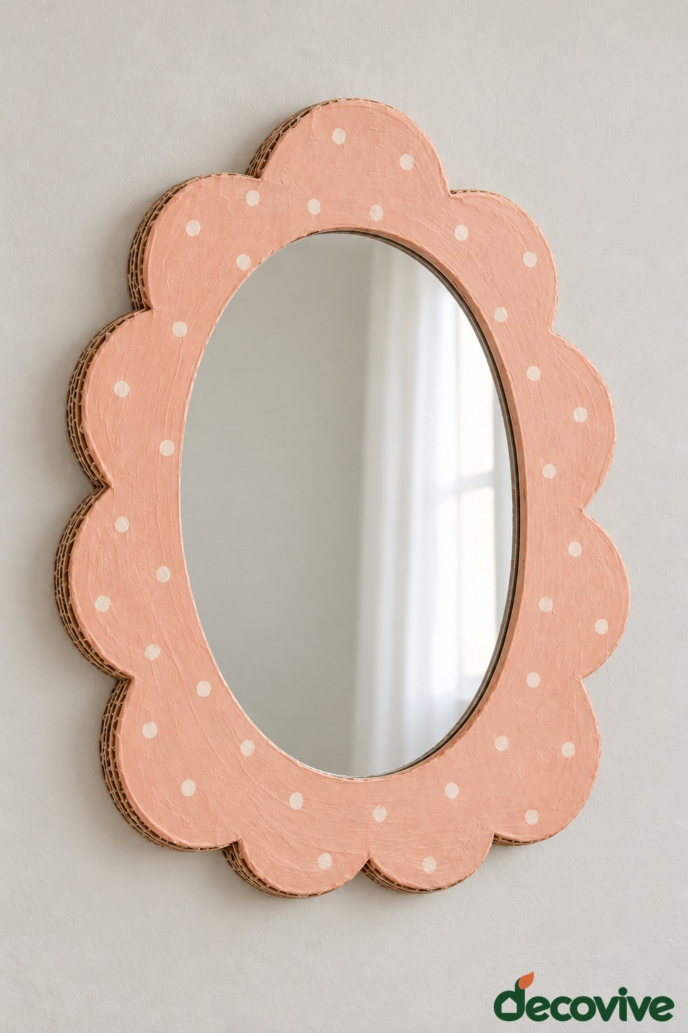Oval mirror with a peach pink scalloped cardboard border and cream dots