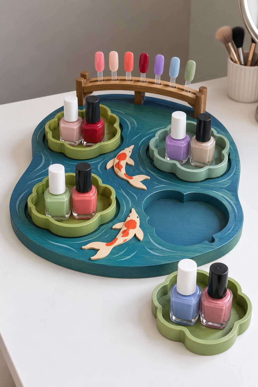 Blue koi pond themed tray with removable green lily pad bottle holders and a small bridge supporting swatches