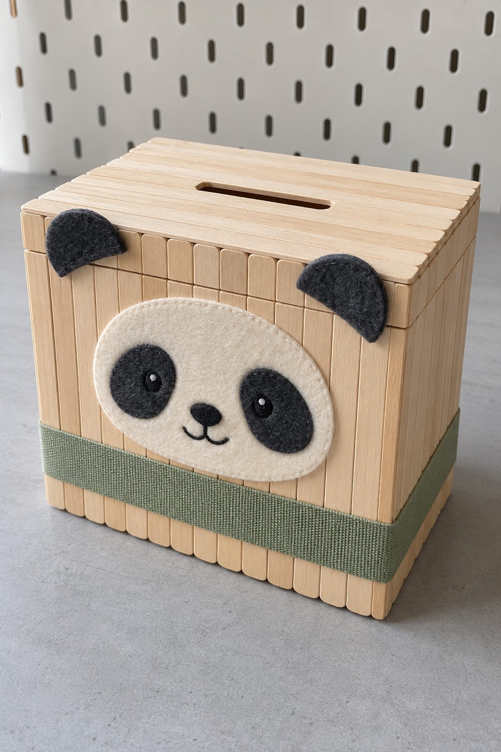 Natural wood slat cube coin bank with a felt panda face, black ears and a sage band near the base