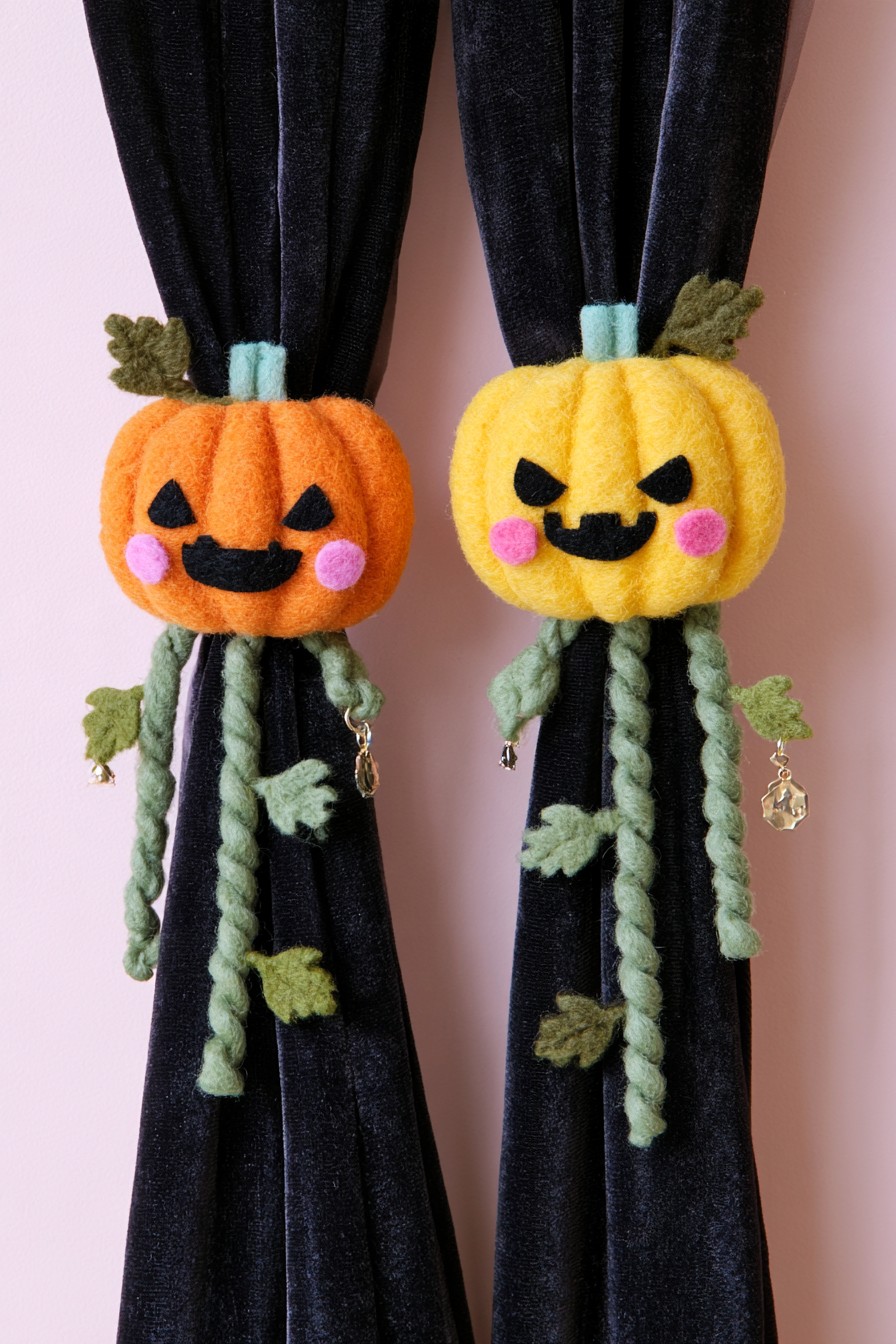 Orange and yellow soft pumpkin tiebacks holding a black curtain