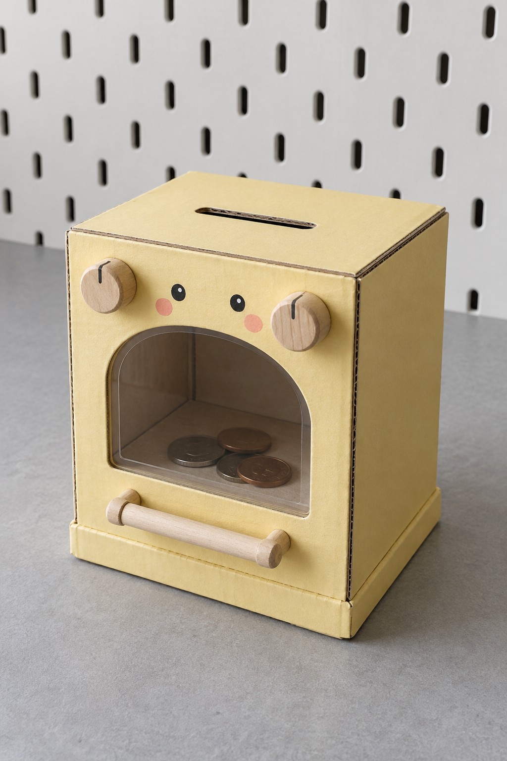 Yellow miniature oven coin bank with a clear arched front window, wooden knobs and a low handle