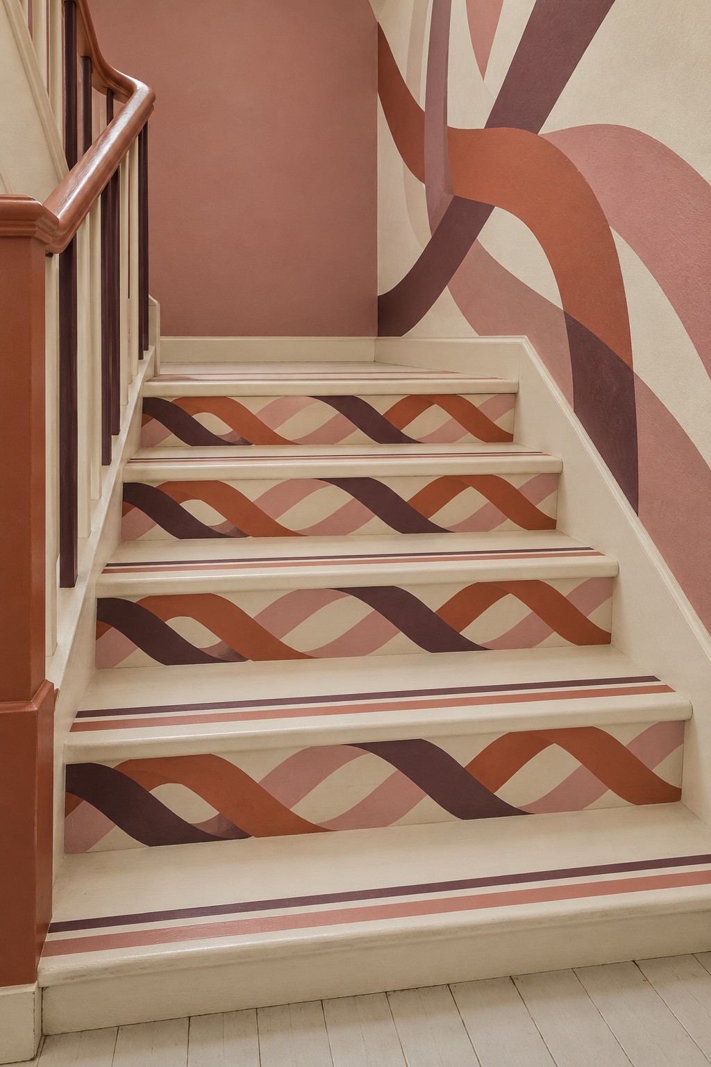 Cream staircase with interlacing rose and terracotta riser patterns and broad curved wall bands