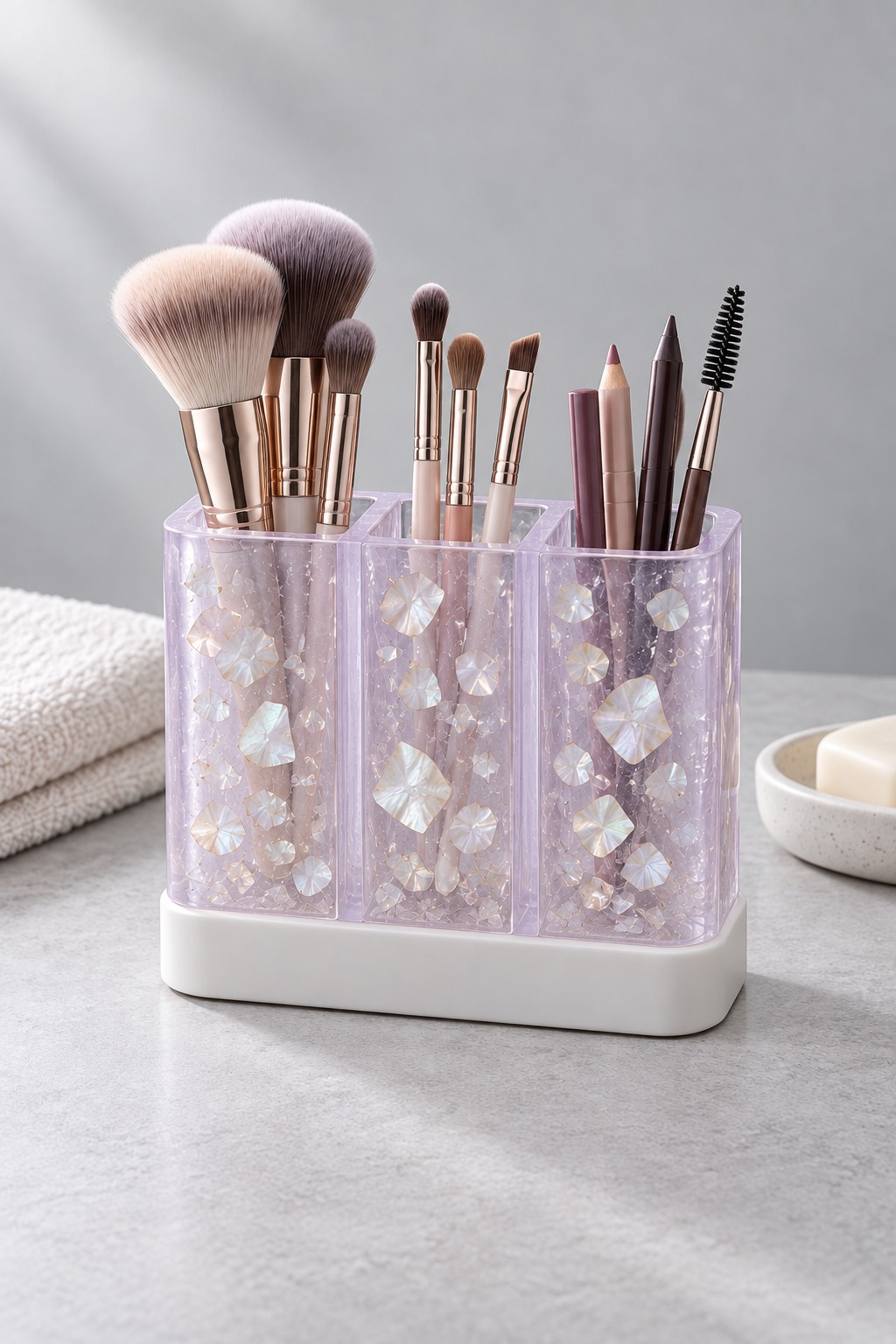 A three compartment lilac resin makeup brush organizer with pearly flakes and a white base.