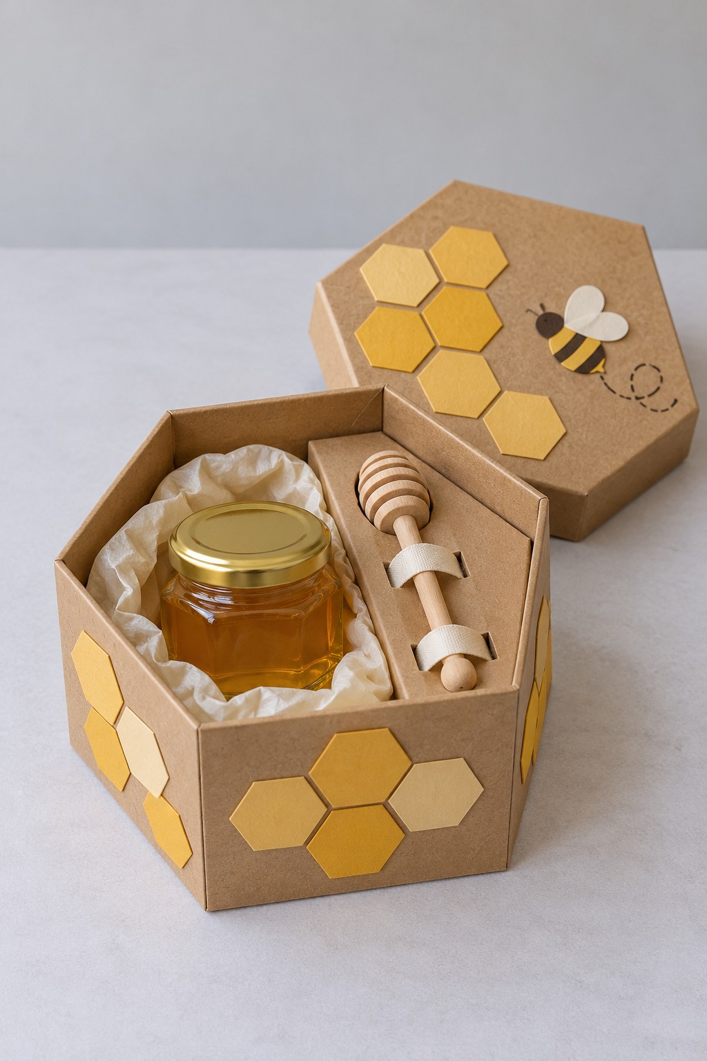 Hexagonal kraft honeycomb box holding a sealed honey jar and wooden dipper beside a bee decorated lid