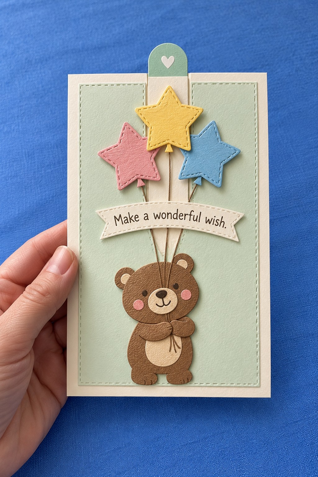 Sage birthday card with a brown teddy bear, three pastel stars, a banner, and a heart topped tab