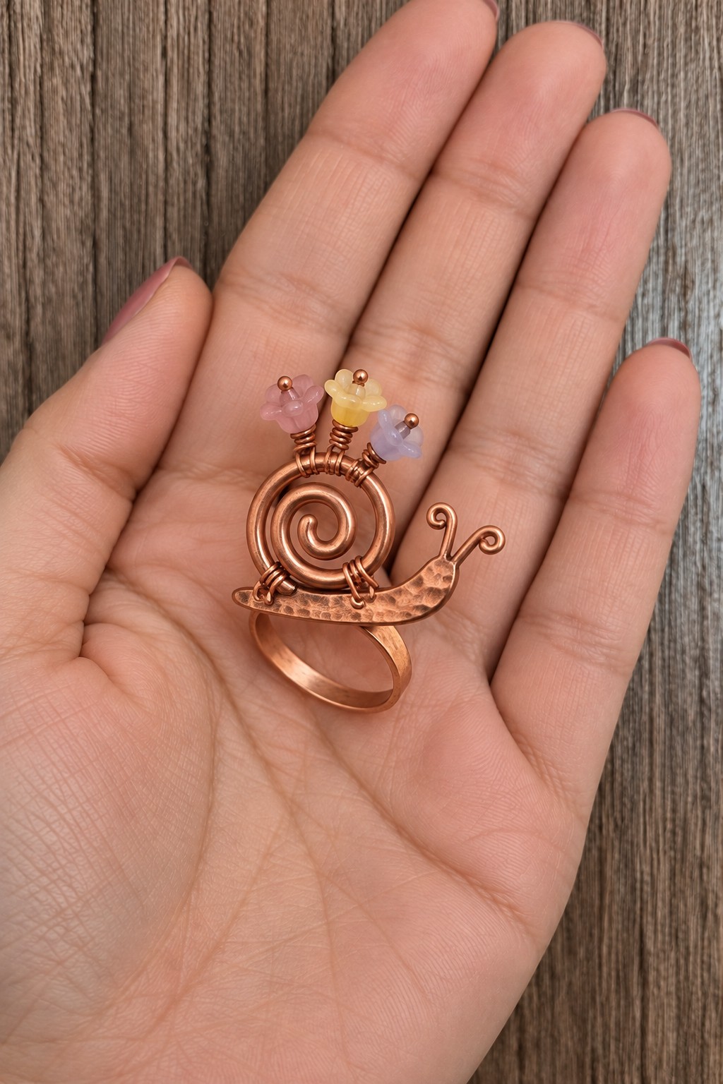 Copper snail ring with a spiral wire shell and three pastel flower beads