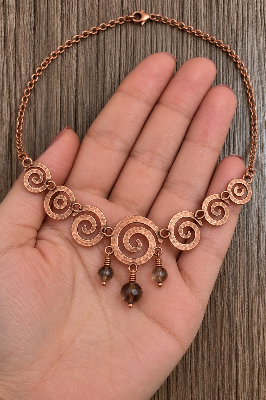 Copper necklace with seven graduated spirals and three smoky colored bead drops