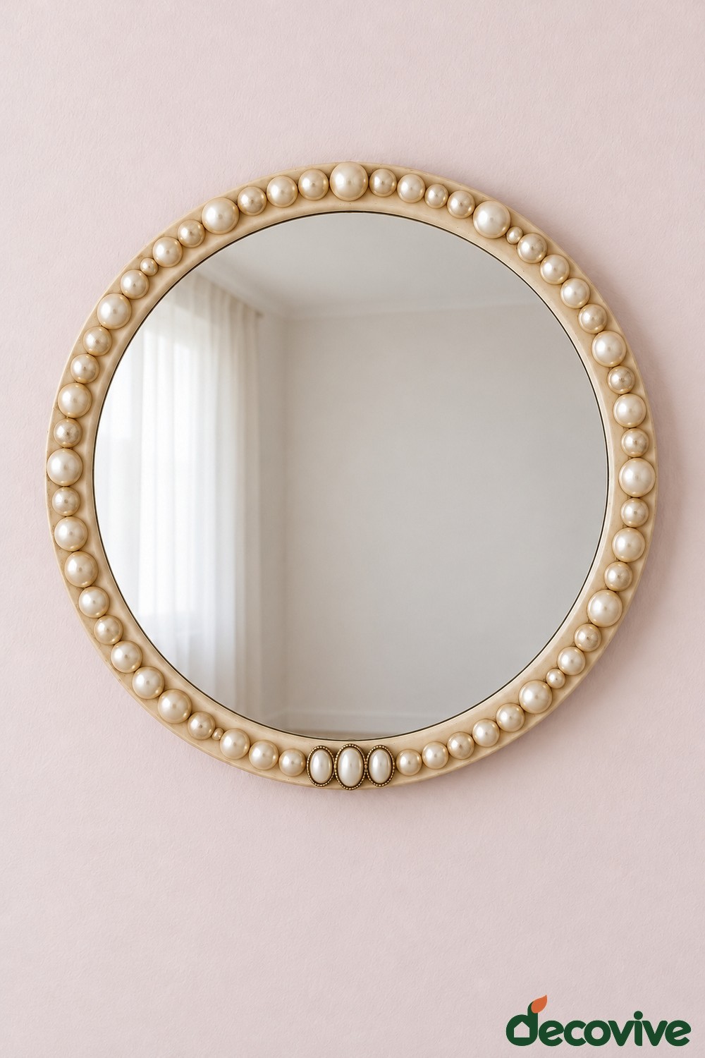 Round mirror with a single border of cream faux pearls on a pink wall