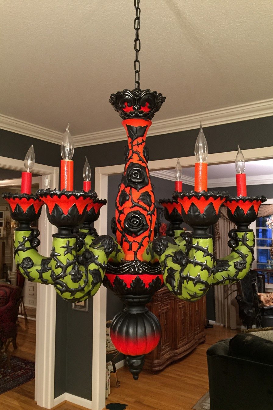 Chandelier painted orange and lime green with sculpted black roses and thorny vines