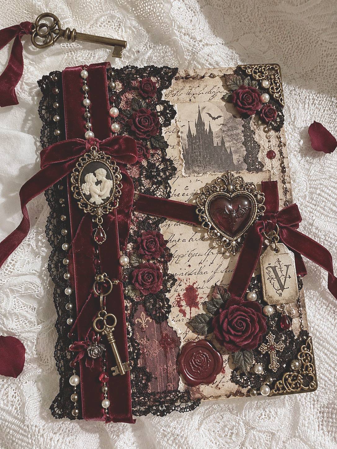 Gothic journal with crossed burgundy ribbons, a heart ornament, black lace, and rose details