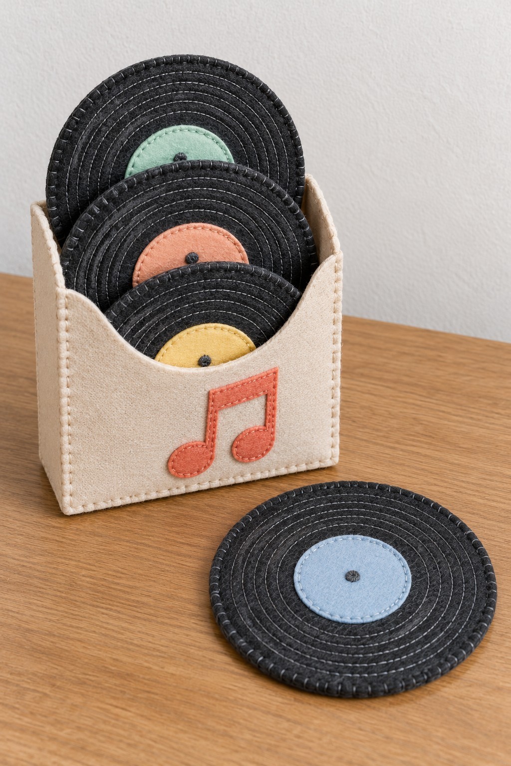 Black felt record coasters with pastel centers stored in a cream sleeve with a music note