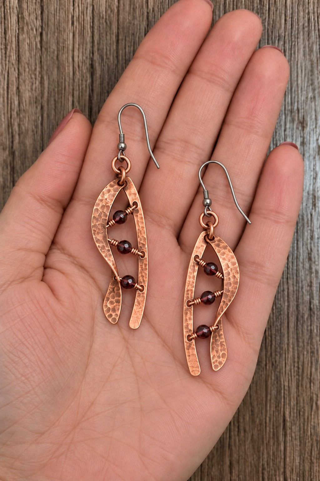 Long split copper leaf earrings with three burgundy beads inside each opening