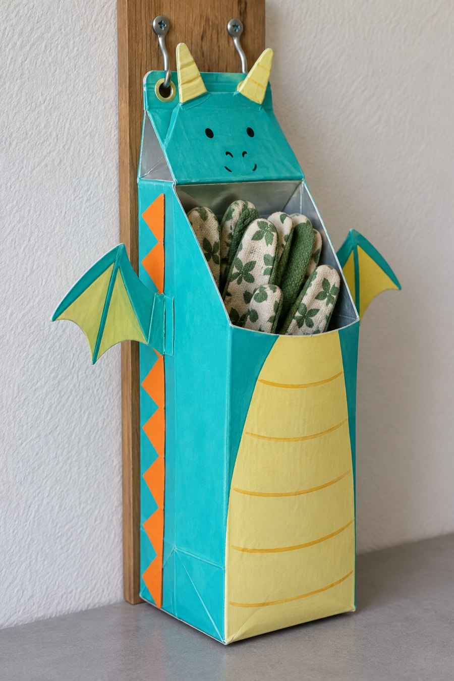 Turquoise and yellow dragon carton pocket hanging from two hooks with gloves inside