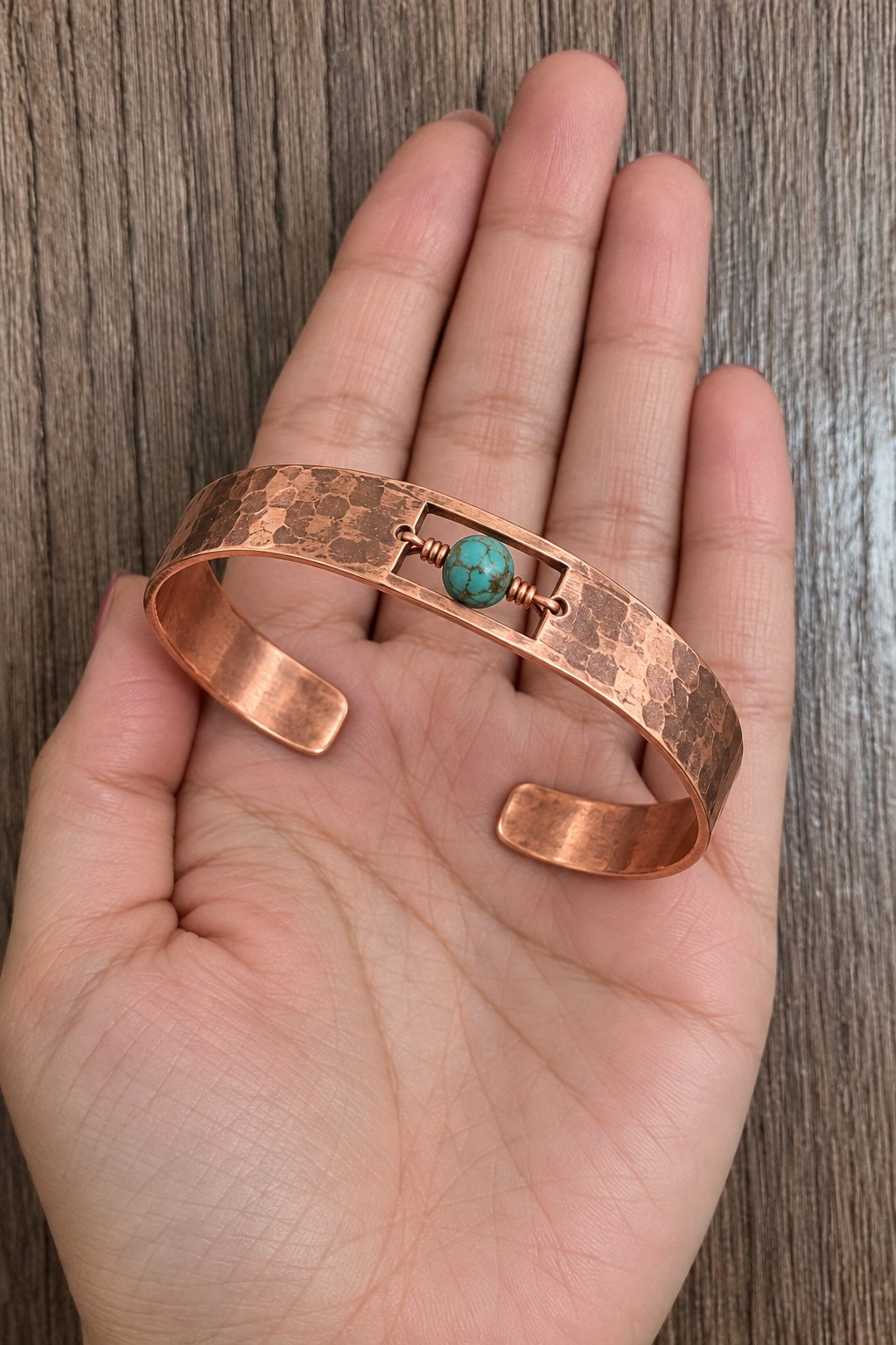 Hammered copper cuff with a rectangular central opening and one turquoise colored bead