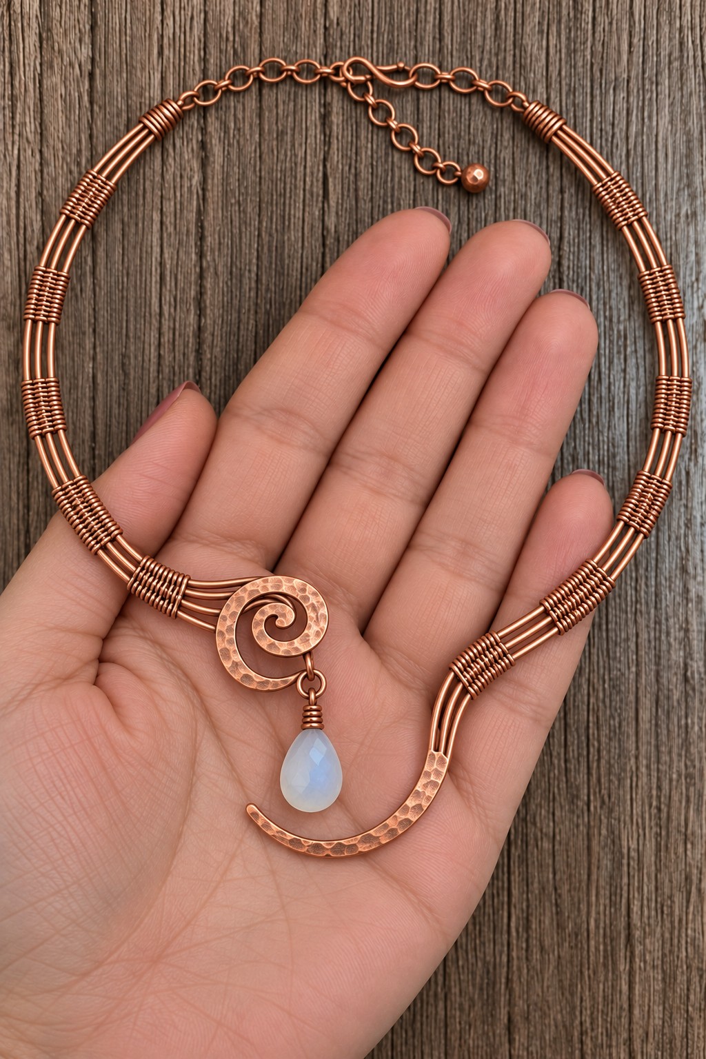 Copper wire collar necklace with bound parallel strands, an open spiral front, and a pale blue drop