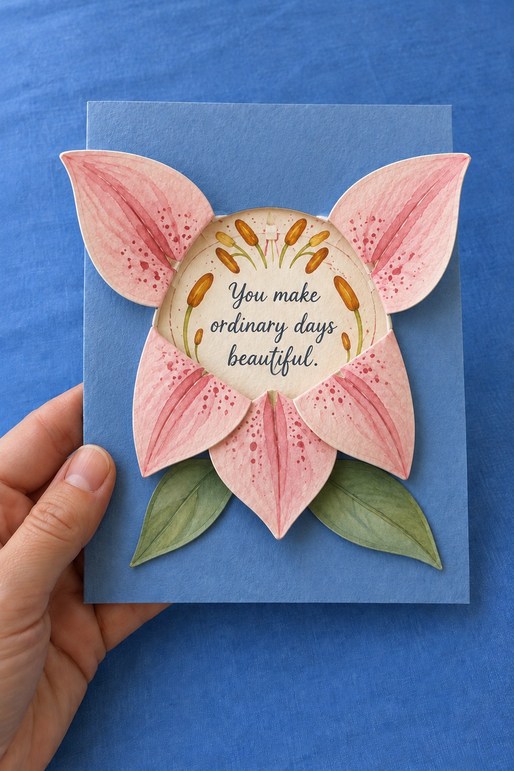 Blue birthday card with large pink lily petals surrounding a cream circular message