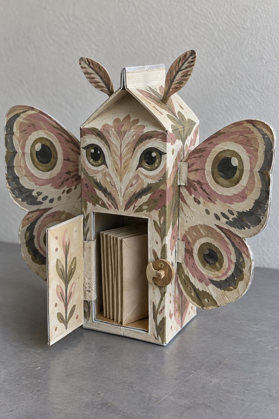 Botanical moth shaped carton cabinet with broad wings and a small open door