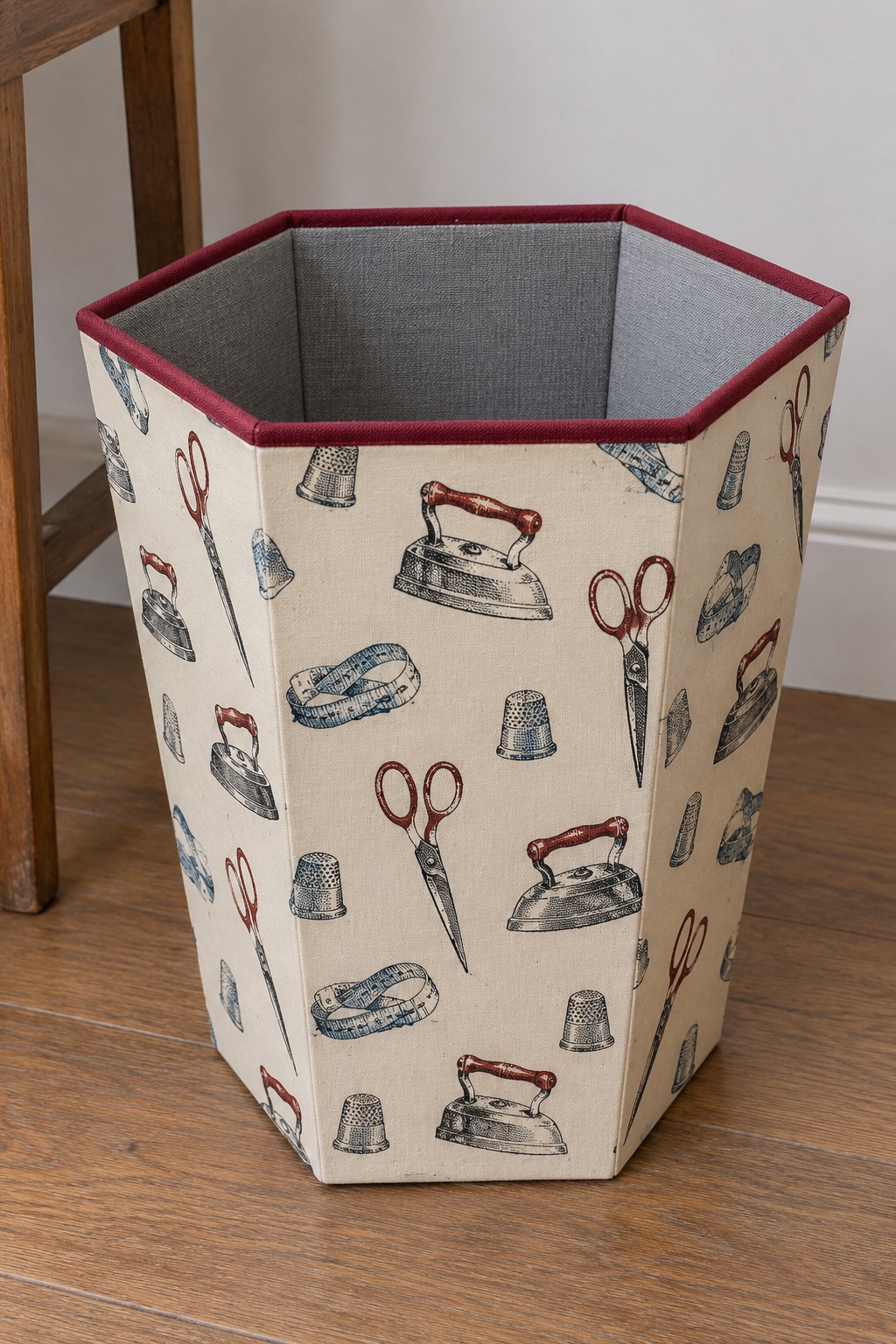 Hexagonal fabric covered wastebasket printed with irons, scissors and thread spools