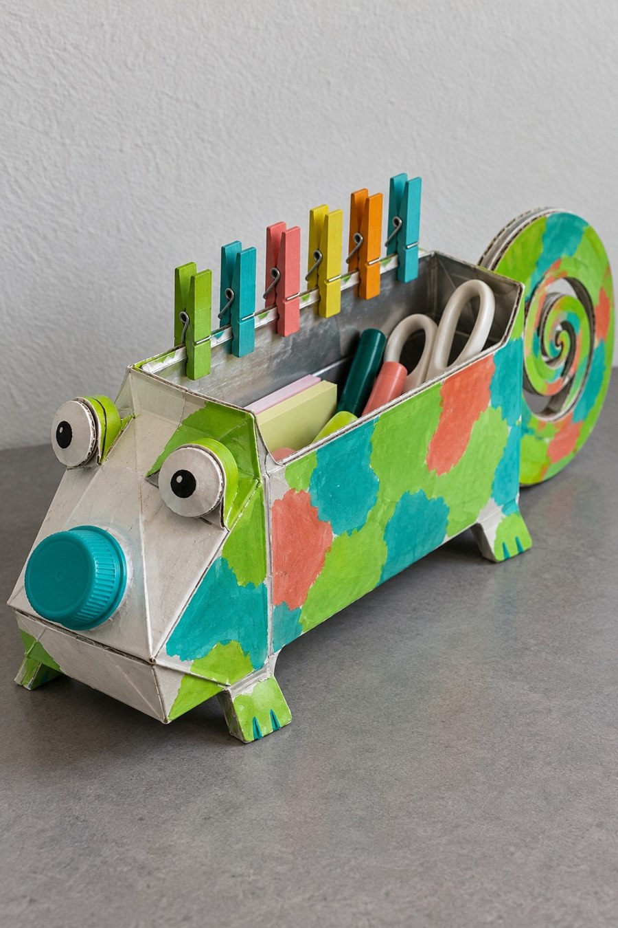 Colorful chameleon carton organizer holding scissors and pens with a curled tail