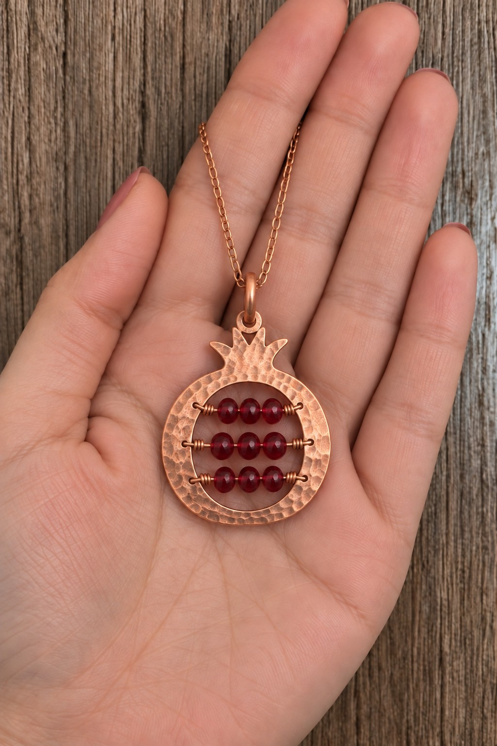 Pomegranate shaped copper pendant with three horizontal rows of dark red beads
