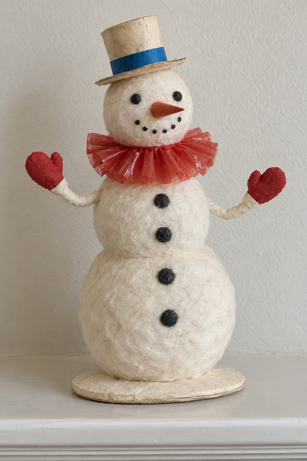 White textured snowman with a cream top hat, red collar and mittens on a small oval base