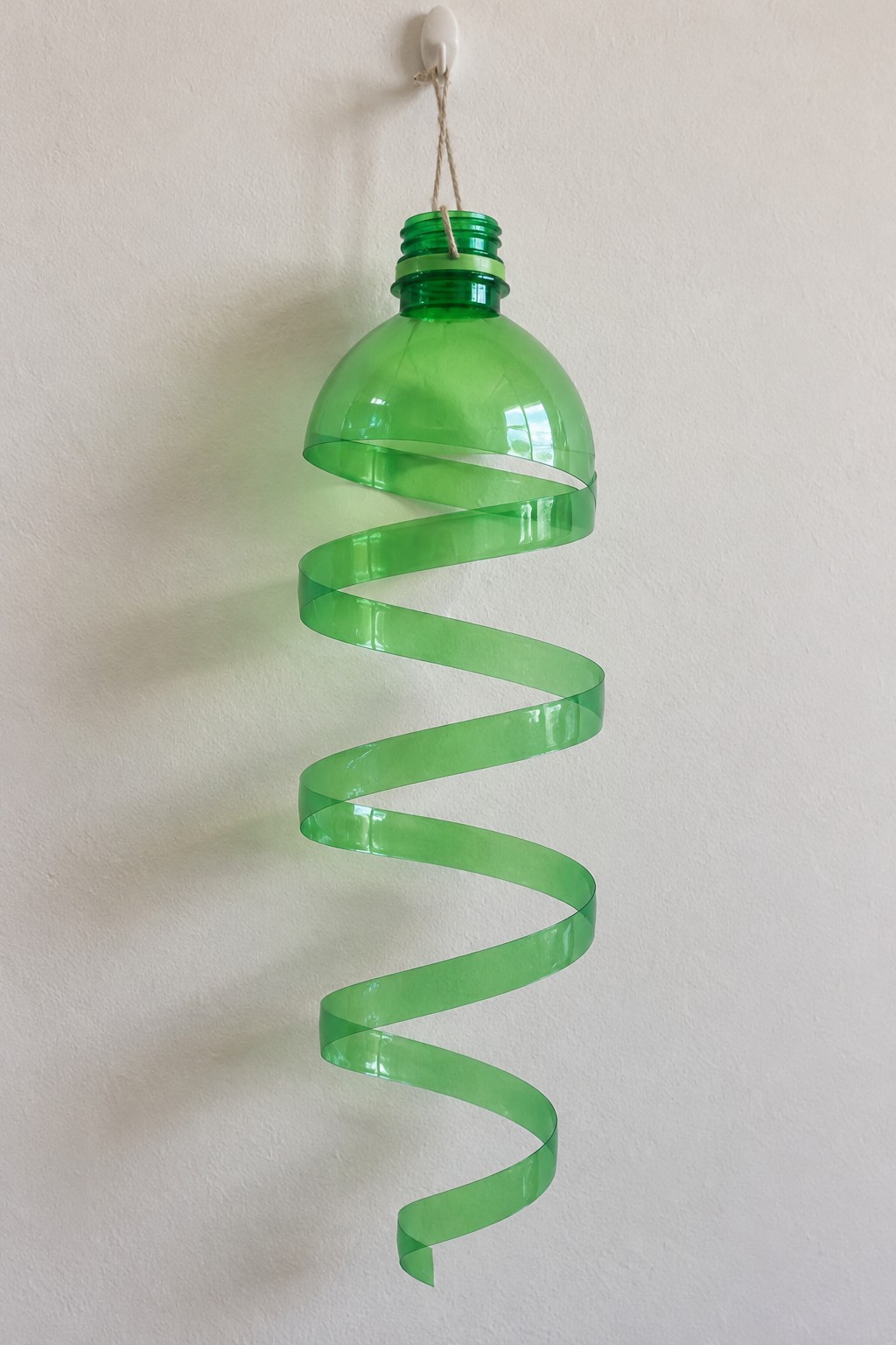 Green plastic bottle shoulder hanging from cord with a continuous spiral strip extending beneath it