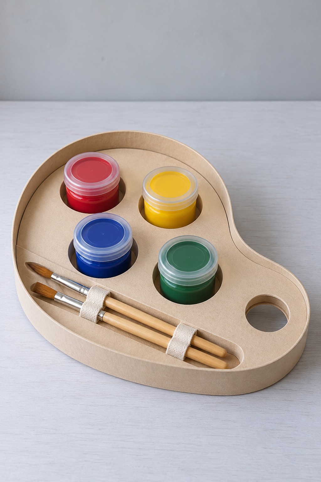 Kraft palette shaped tray with four lidded paint pots in round recesses and two brushes under fabric loops