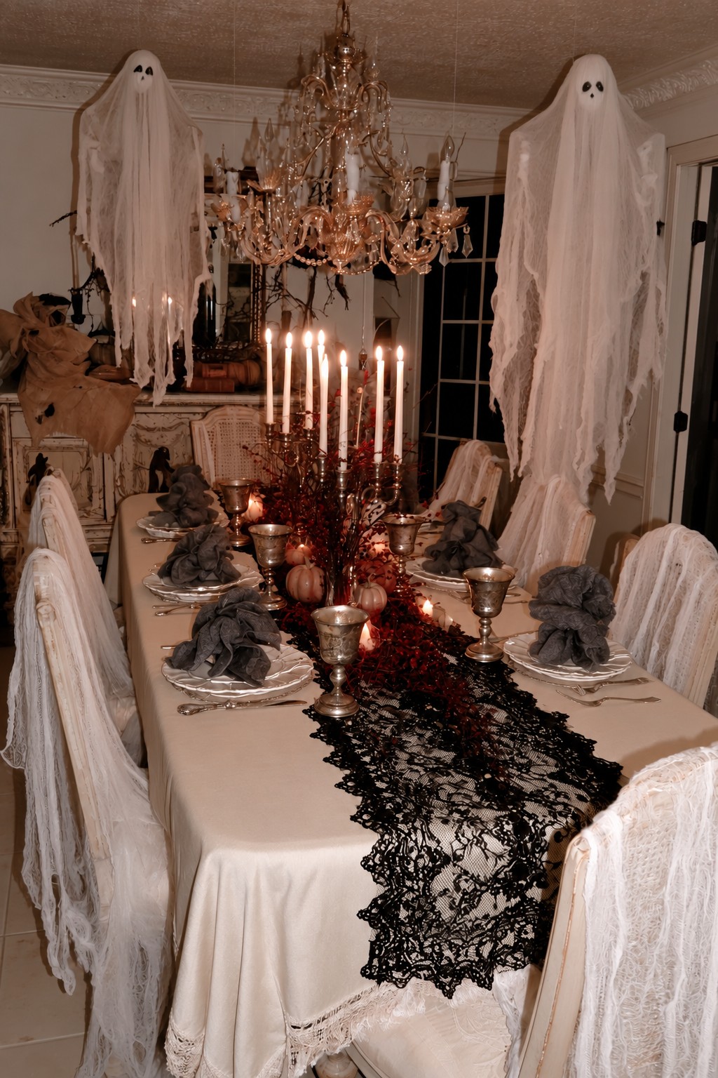 White fabric ghosts above an ivory table with black lace, silver-toned goblets, and gauze-covered chairs