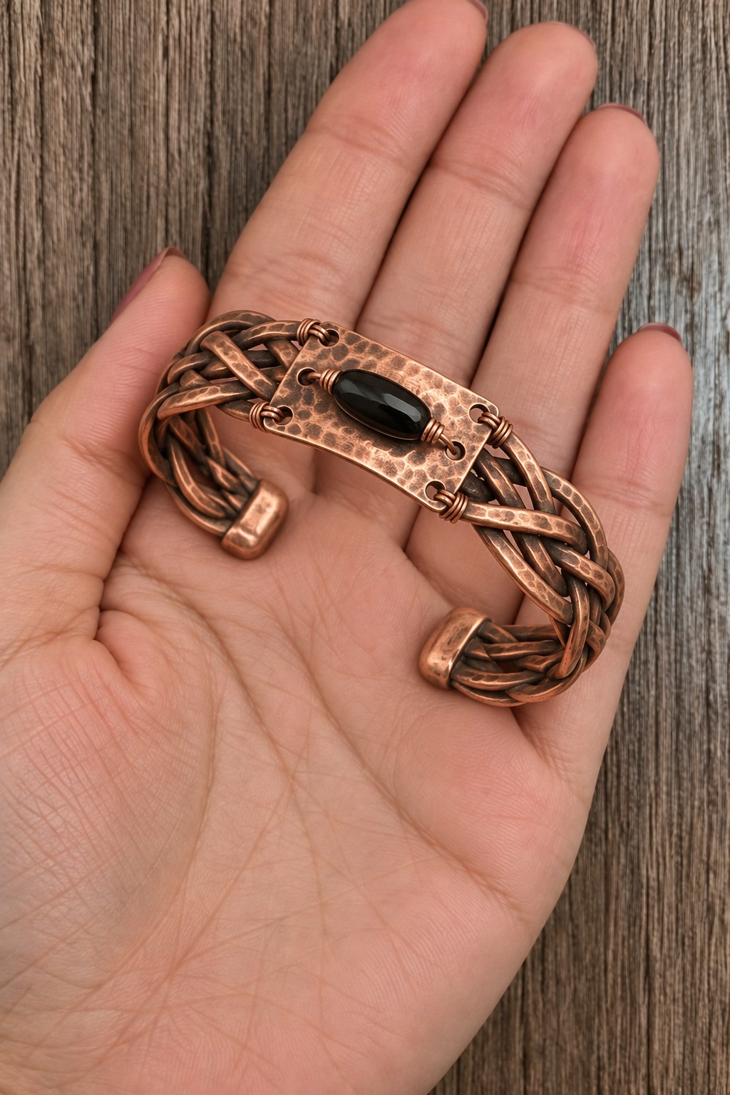 Wide braided copper cuff with a hammered central plate and an elongated black bead