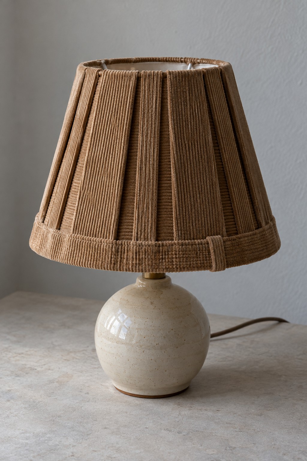 Brown corduroy pleated lampshade on a small ceramic table lamp