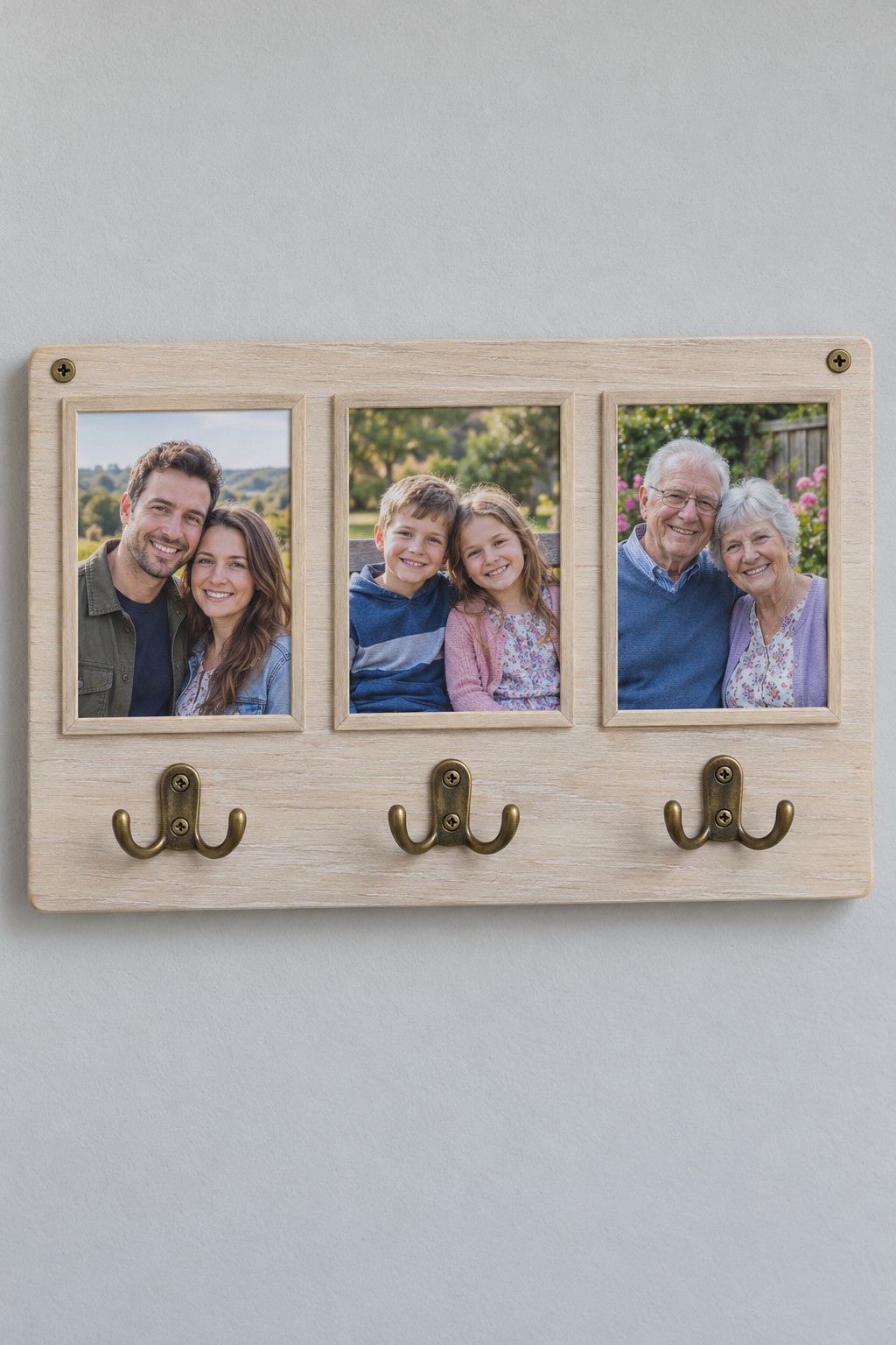 Pale wooden wall rack with three framed family portraits above three brass key hooks