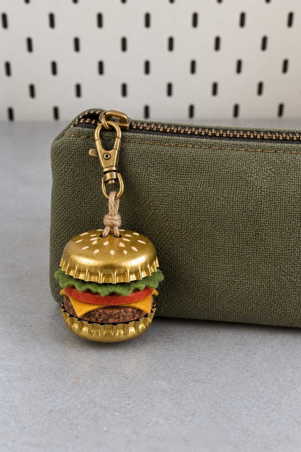 Miniature burger zipper charm with gold bottle cap buns, green felt lettuce, red tomato, yellow cheese, and a brown patty