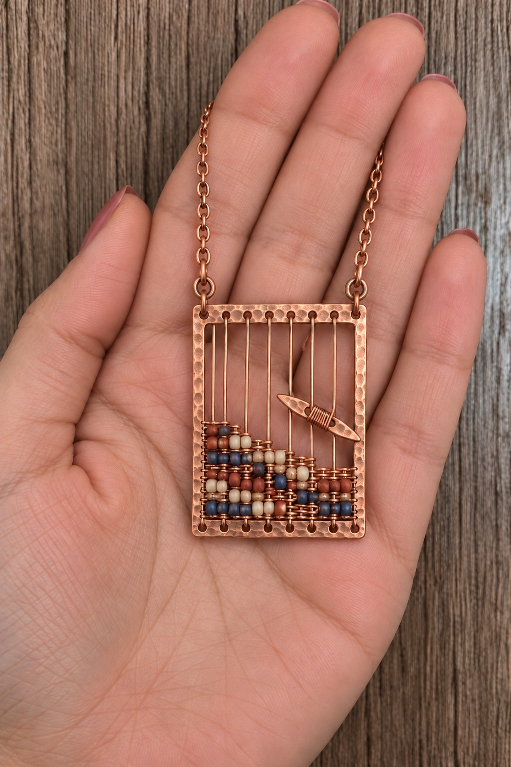 Rectangular copper frame with vertical bead wires, a multicolored bead pattern below, and a small copper boat
