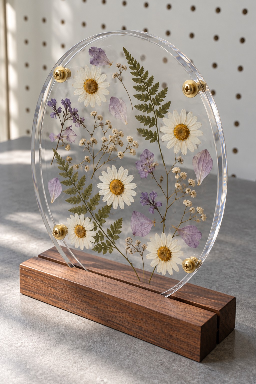 Pressed daisies purple flowers and a fern displayed between clear acrylic ovals in a wooden base