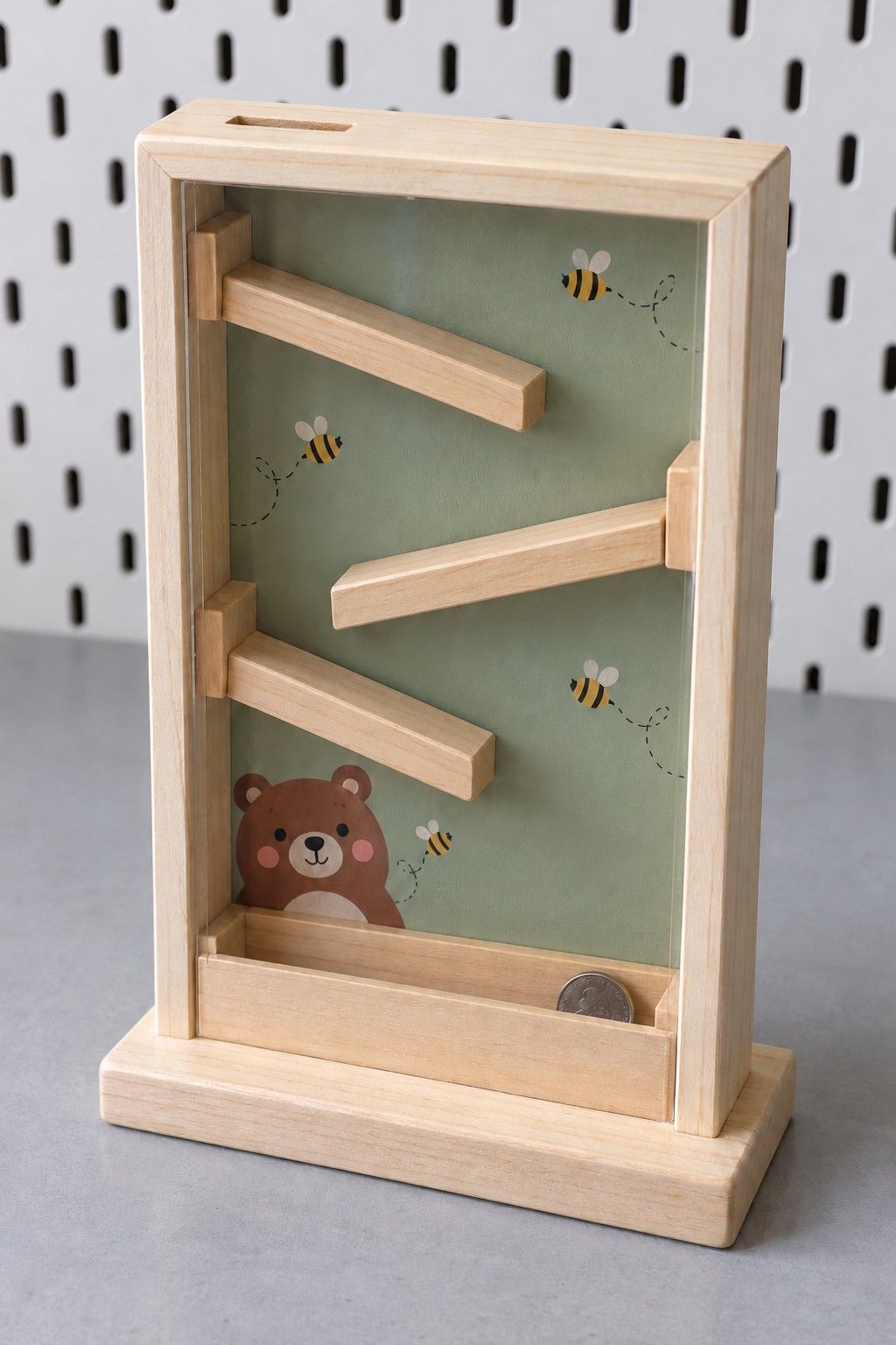 Tall clear front wooden coin bank with three alternating ramps, bee motifs and a bear at the bottom