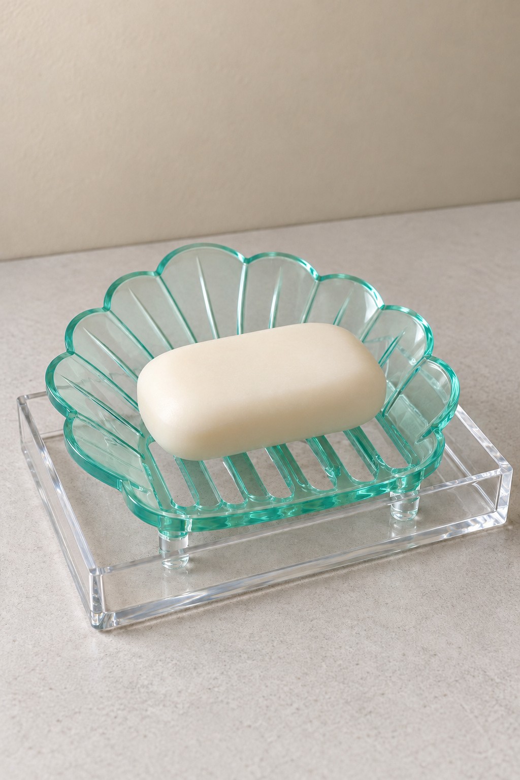 Mint shell shaped draining soap dish raised above a clear acrylic catch tray